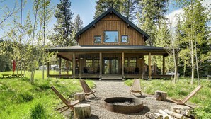 A wooden cabin with a porch, a fire pit, and outdoor seating.