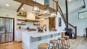 A spacious kitchen with a large island, wooden shelves, and a built-in stove.