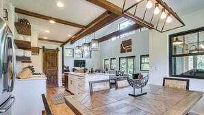 A spacious kitchen with a large island, wooden beams, and pendant lighting.