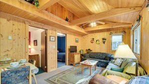 L'intérieur d'un chalet en bois comprend un coin repas, un canapé et un téléviseur.