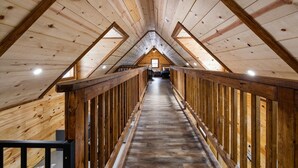 Habitación en el ático con vigas, suelo y barandilla de madera.