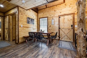 Interno in legno con tavolo da pranzo, sedie, una porta di legno e un grande tronco d'albero.