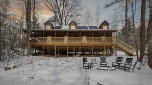 A wooden cabin with a covered deck and outdoor seating area. - 3 Cabins | 30+ | 3-Hot Tubs| DogOK | FirePit (Campton)