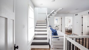 Una escalera moderna que conduce a un dormitorio con una puerta blanca y un edredón azul en la cama.
