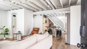 Un amplio espacio de sala con un sofá, una mesa de comedor y una escalera que sube a un nivel superior.