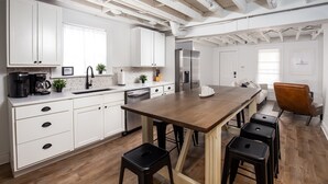 Una cocina moderna con armarios blancos, una isla de madera y taburetes de bar.