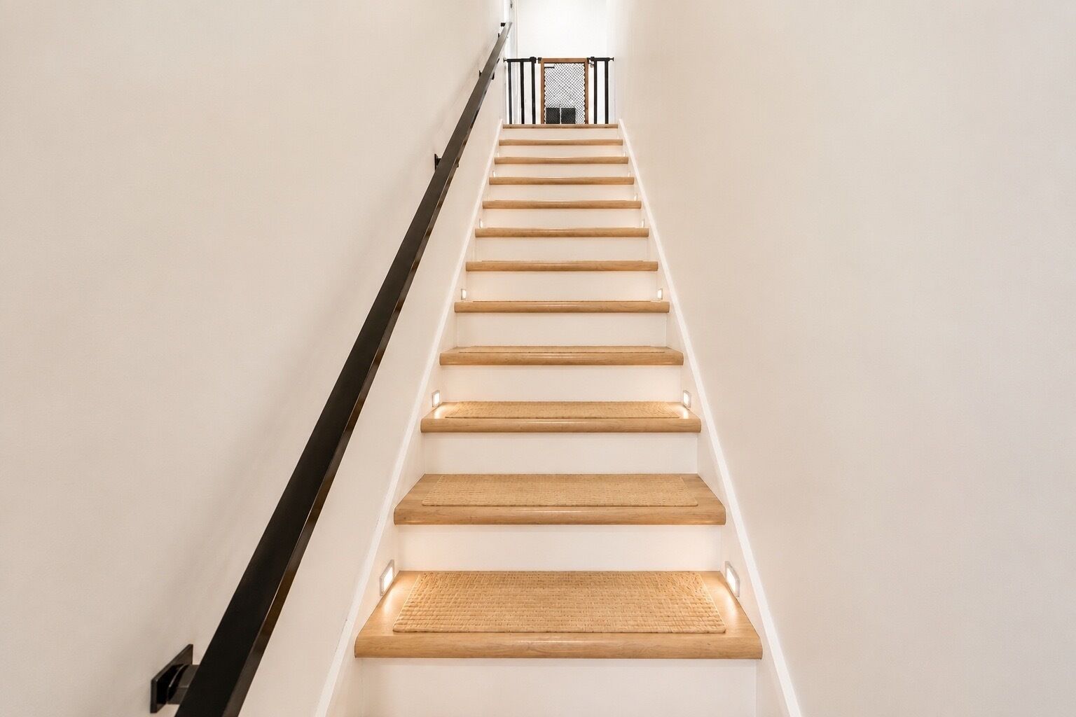 Un escalier avec des marches en bois et une rampe noire.