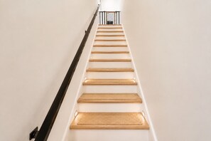 Una escalera con escalones de madera y barandal negro.