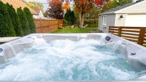 A hot tub with water jets, surrounded by a wooden fence, a hammock, and trees with autumn foliage. - Charming Plymouth retreat • hot tub • fire pit

 (Plymouth)