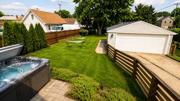 A backyard with a hot tub, a wooden fence, a lawn, and a shed.