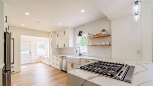 A modern kitchen with white cabinets, a stainless steel refrigerator, and a marble countertop. - Charming Plymouth retreat • hot tub • fire pit

 (Plymouth)