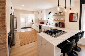 Una cocina moderna con una isla central, electrodomésticos de acero inoxidable e iluminación colgante.