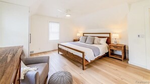 A bedroom with a wooden bed, bedside tables, a chair, and a window. - Charming Plymouth retreat • hot tub • fire pit

 (Plymouth)