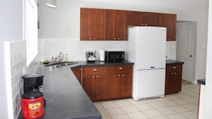 A kitchen with wooden cabinets, a white refrigerator, a microwave, and a coffee maker. - Country Oasis in the Village (Elora)
