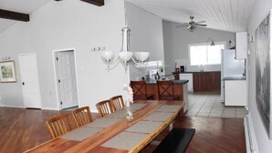 A spacious dining area with a long wooden table, benches, and a chandelier. - Country Oasis in the Village (Elora)