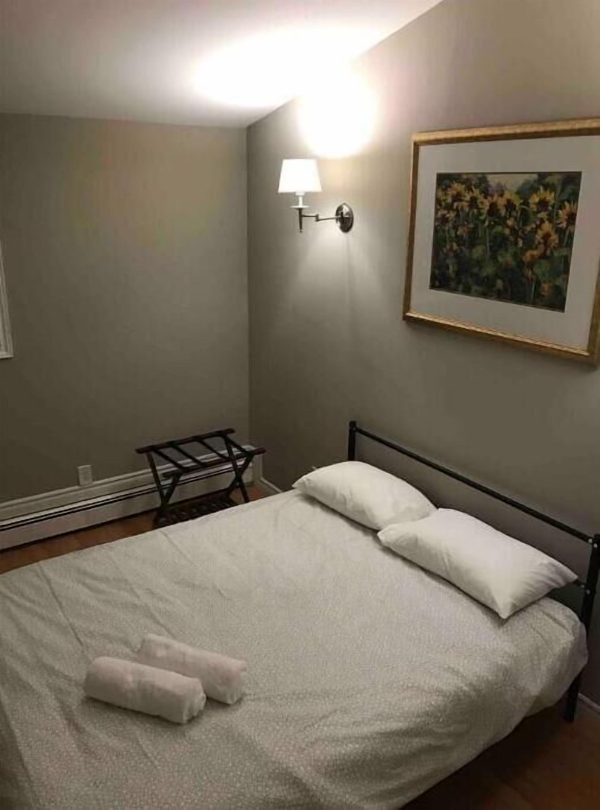 Une chambre à coucher avec un lit, une table de chevet, une lampe et un tableau encadré au mur.