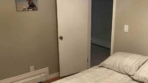 A bedroom with a bed, a door, a wall-mounted picture, and a radiator. - Country Oasis in the Village (Elora)