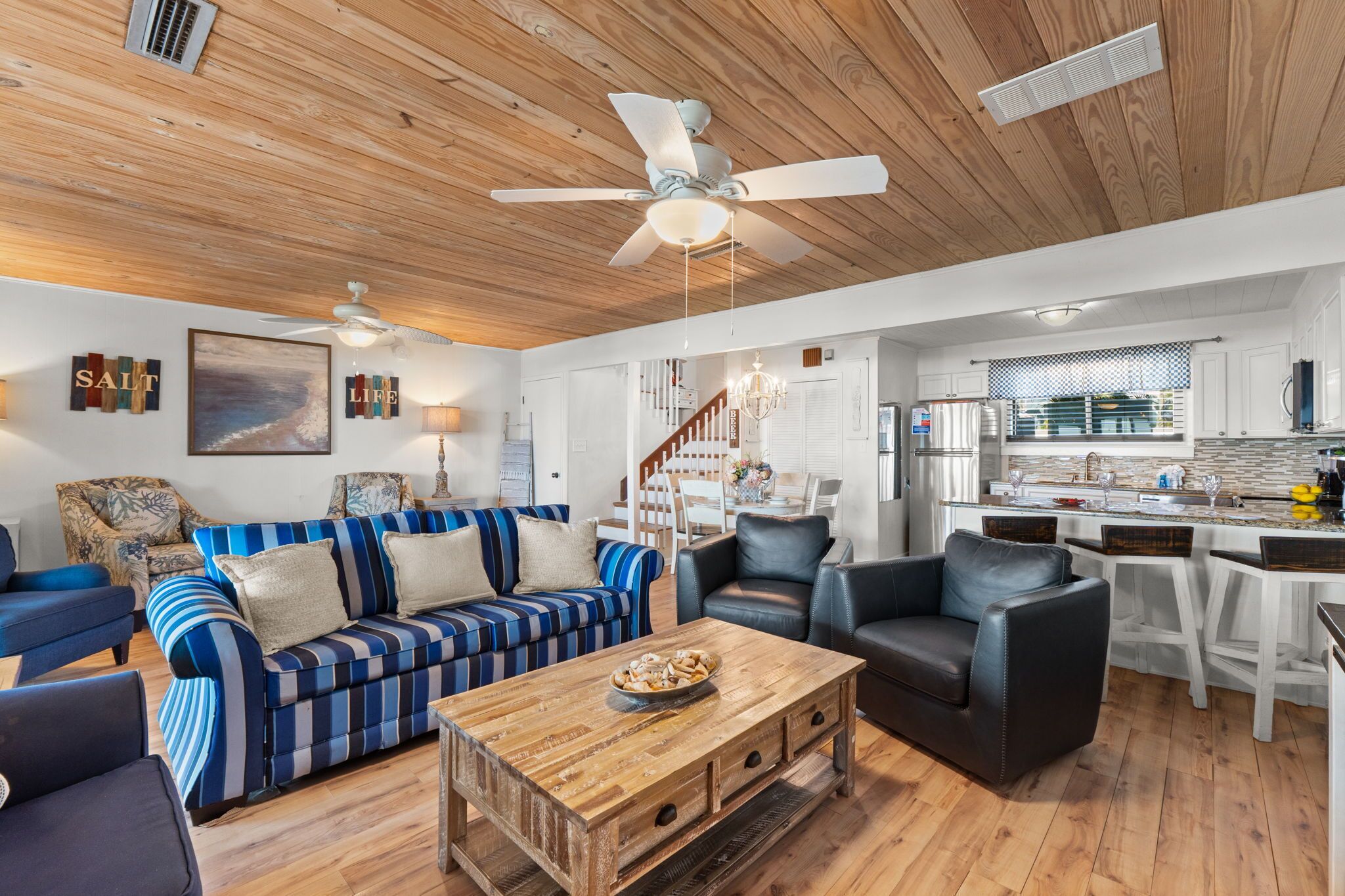 A living room with a striped sofa, a coffee table, and a dining area with a chandelier.