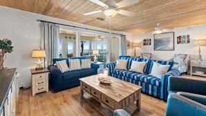 A living room with wooden ceilings, two sofas, a coffee table, and a lamp. - Sunny Beach by Book That Condo (Panama City Beach)