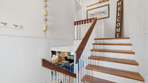 A wooden staircase with a white railing, a 'WELCOME' sign, and a framed picture on the wall. - Sunny Beach by Book That Condo (Panama City Beach)