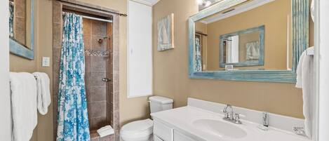 Un baño con ducha, inodoro, lavabo y un espejo grande con iluminación.