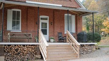 A brick house with a porch, a wooden staircase, and a bench.