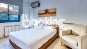 Ein Schlafzimmer mit einem Bett, einem Sessel, einem Gemälde und einem Fenster.