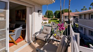 A balcony with outdoor furniture, a pool, and palm trees. - Los Balcones de Palm Springs Mid-Century Modern Designer Condo, City ID #068484 (Palm Springs)