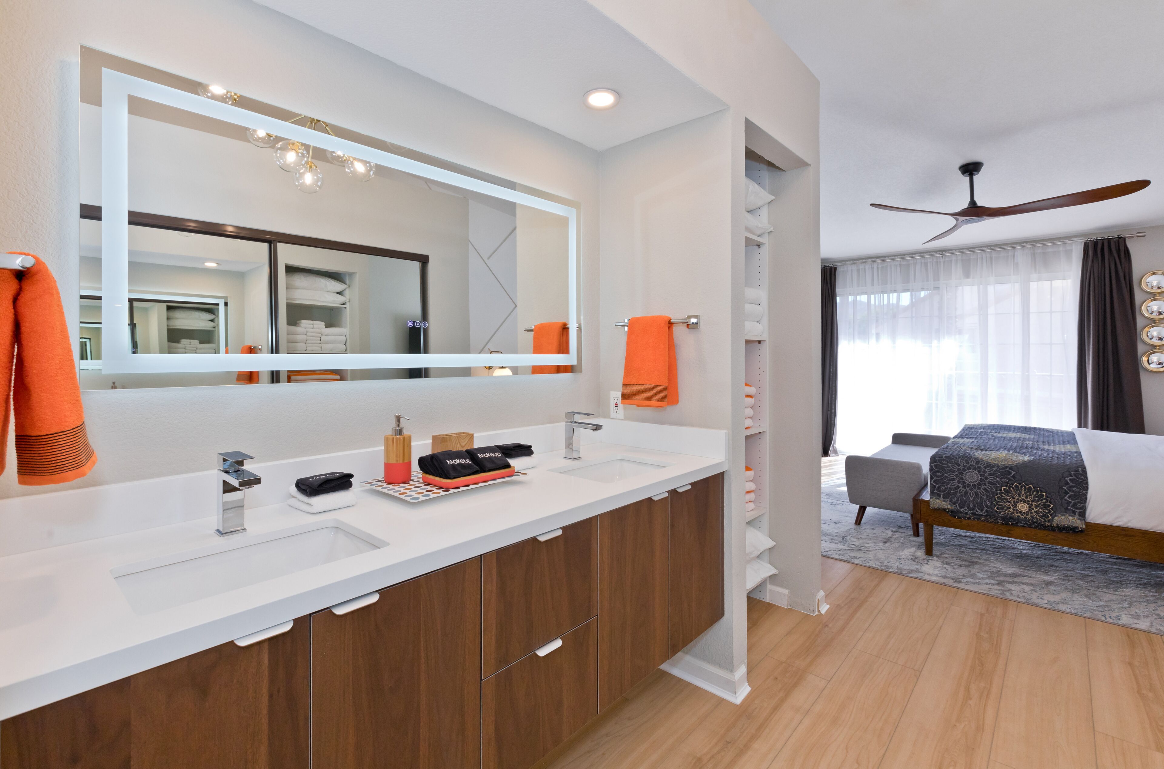 A modern bathroom with a large mirror, dual sinks, and wooden cabinets.