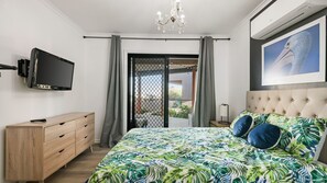 A bedroom with a bed, a TV, a dresser, and a balcony. - Number Thirty One Smiths Beach Phillip Island (Smiths Beach)