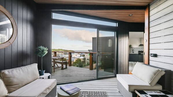 A modern interior with a balcony, a sofa, a table, and a potted plant.