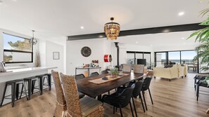 A modern kitchen with a dining area, large windows, and a view of the outdoors. - Number Thirty One Smiths Beach Phillip Island (Smiths Beach)
