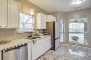 Una cocina con armarios blancos, un refrigerador de acero inoxidable y un lavavajillas.