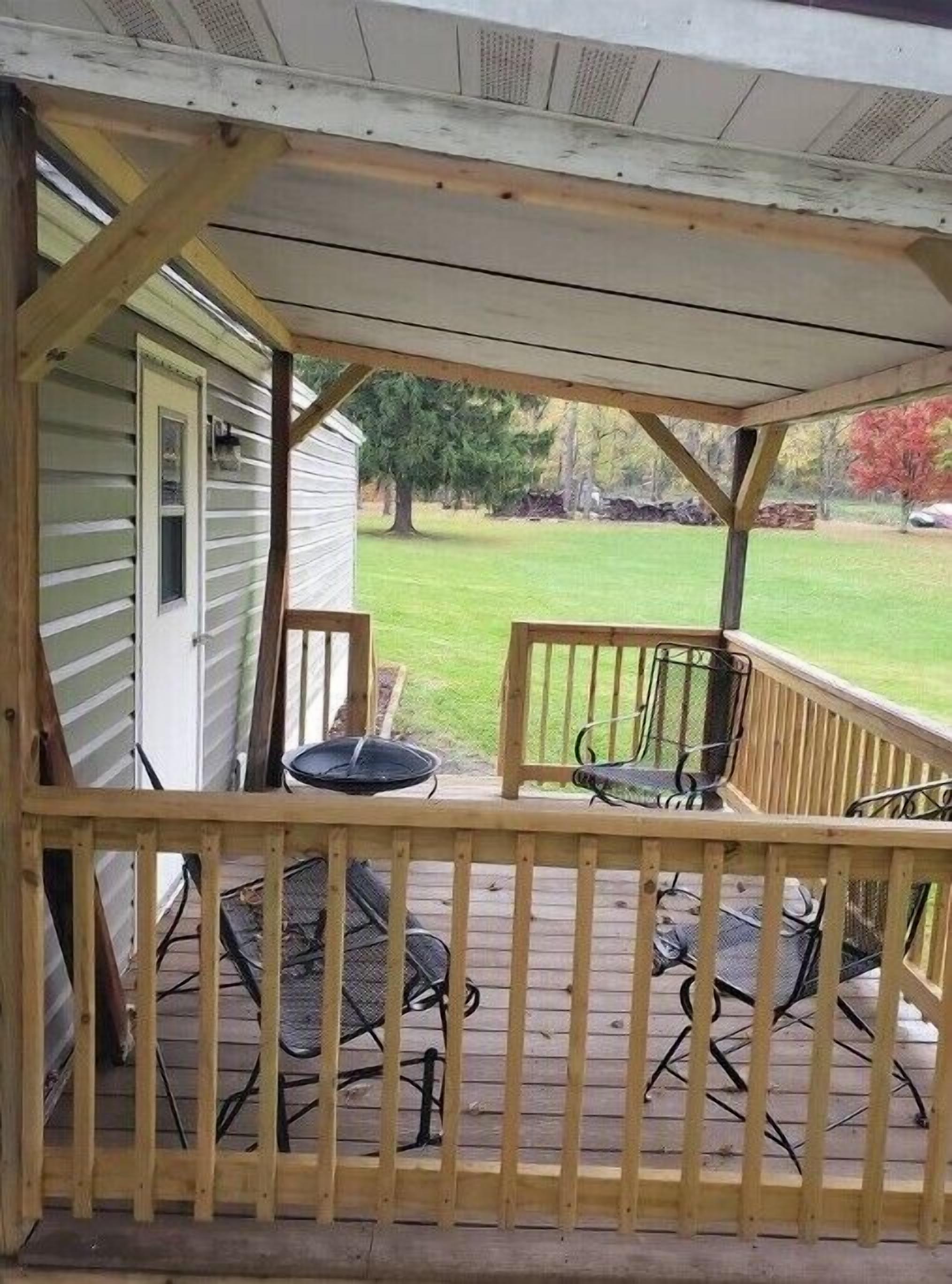A wooden deck with a railing, a small table, and two chairs.