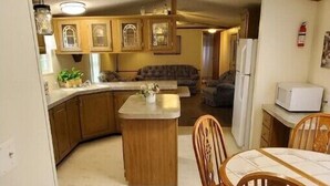 Una cocina funcional con armarios de madera, una isla central y una zona de comedor con sillas de madera.