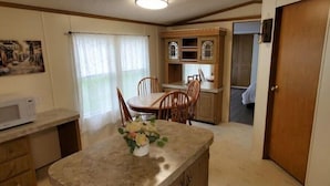Una cocina compacta con comedor, armarios de madera y microondas.