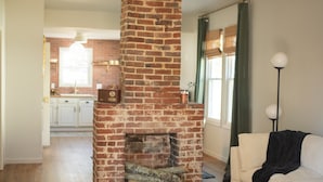 Una sala de estar con chimenea de ladrillo, una mesa de centro de madera y un tapete a cuadros.