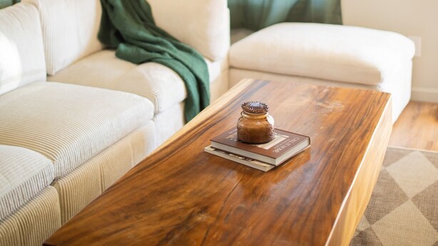 Un salón con una mesa de centro de madera, un sofá blanco y una planta verde.