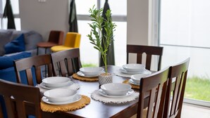 Een eettafel gedekt met witte borden en kommen, omringd door houten stoelen, met een potplant in het midden.