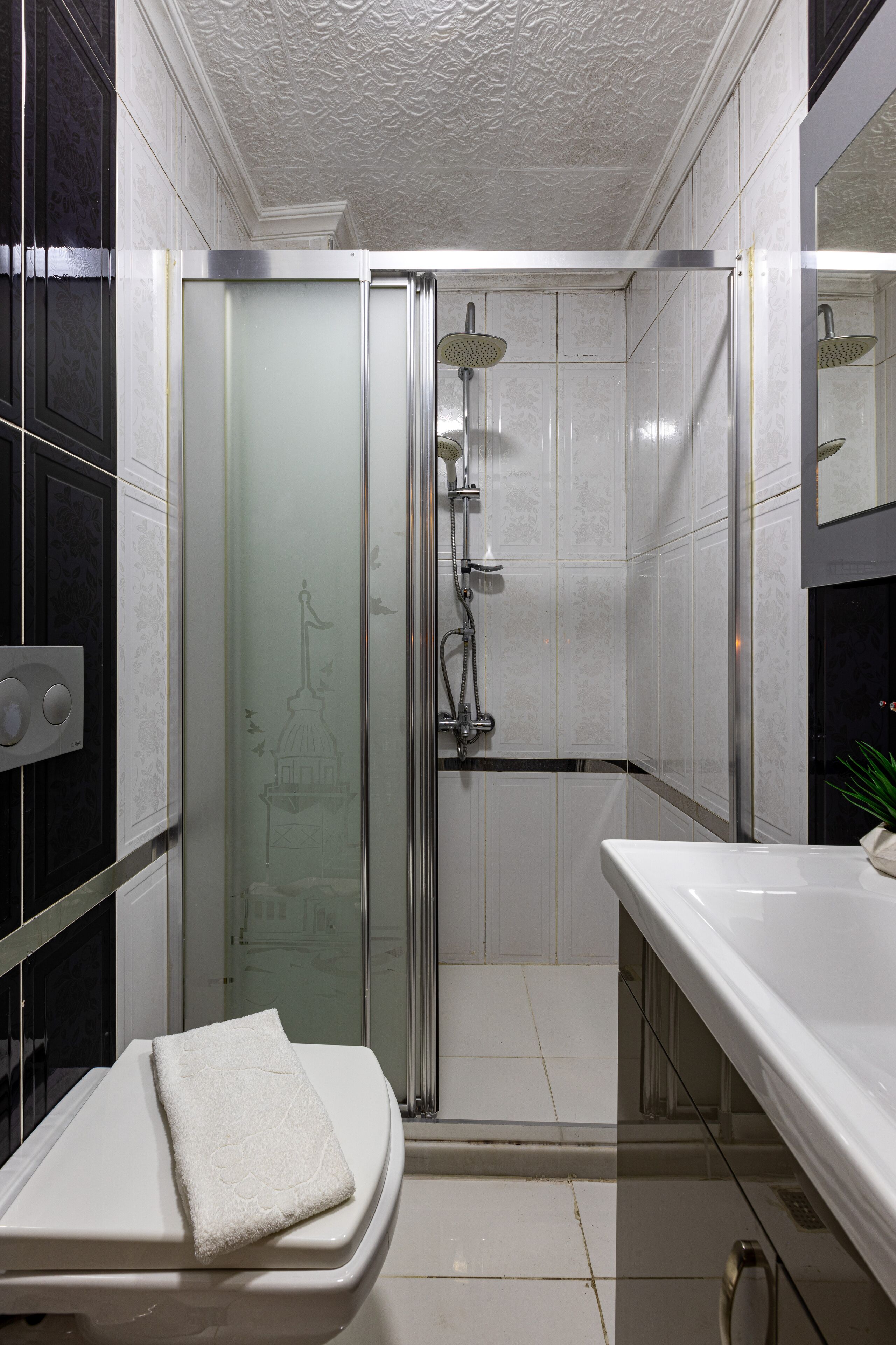 Un baño moderno con ducha de vidrio, lavabo blanco y espejo.
