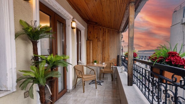 A balcony with a wooden ceiling, potted plants, wicker chairs, and a table. - LINNGA HOTEL & SUITE (Istanbul)