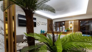 A modern hotel lobby with a large palm tree, a sofa, and a reception desk. - LINNGA HOTEL & SUITE (Istanbul)