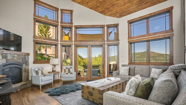 A spacious living room with a fireplace, large windows, and a cozy seating area. - Stunning sunsets, mountain views, and minutes to the mountain. (Steamboat Springs)