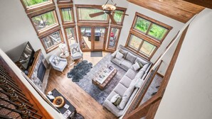 A spacious living room with a large sofa, a coffee table, and a fireplace. There are multiple large windows providing natural light and views of the outdoors. - Stunning sunsets, mountain views, and minutes to the mountain. (Steamboat Springs)