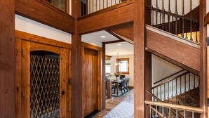 A wooden staircase with a metal railing and a patterned floor mat leading to a dining area. - Stunning sunsets, mountain views, and minutes to the mountain. (Steamboat Springs)