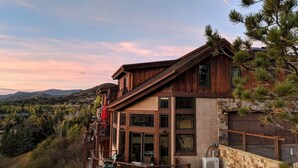 A two-story wooden house with a balcony, large windows, and a view of the surrounding landscape. - Stunning sunsets, mountain views, and minutes to the mountain. (Steamboat Springs)