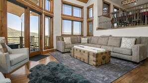 A spacious living room with a large window, a wooden ceiling, and a staircase. - Stunning sunsets, mountain views, and minutes to the mountain. (Steamboat Springs)