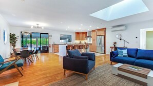 Uma sala de estar moderna com área de jantar, cozinha e um amplo claraboia.
