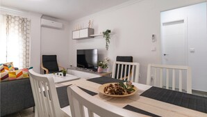 A modern living room with a TV, seating, and a dining area. - Cozy apartment in Sanlúcar de Barrameda (Sanlúcar de Barrameda)