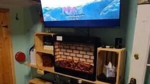 A room with a television mounted on the wall, a fireplace, and a wooden cabinet.